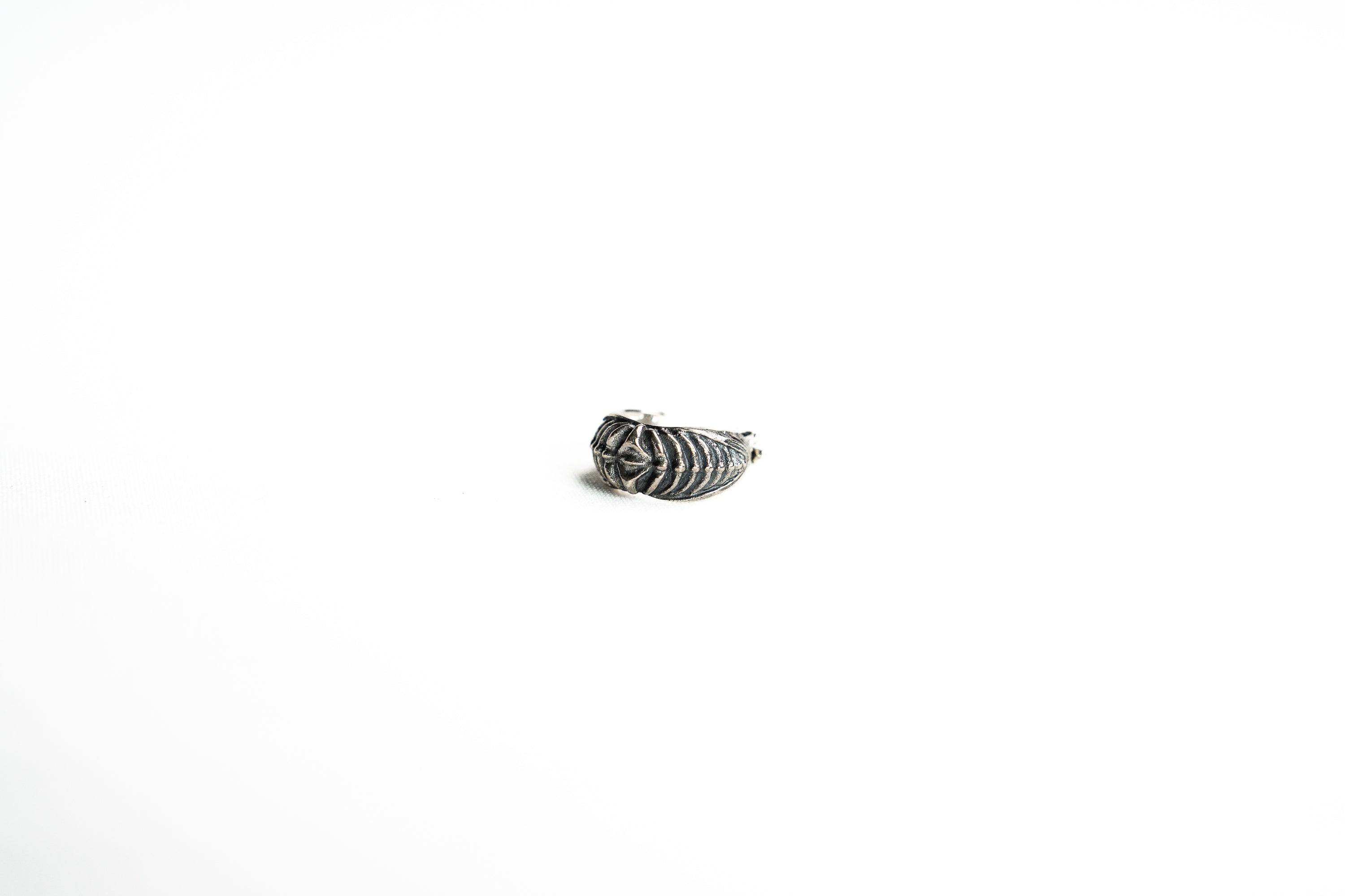 A side-angle shot of the silver bioorganic septum ring, highlighting the intricate geometric and organic patterns that give it a futuristic aesthetic.